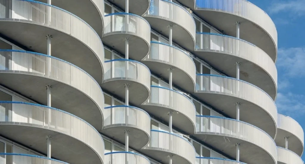 Prospetto di un palazzo condominiale con file di balconi aggettanti e frontalini uniformi.