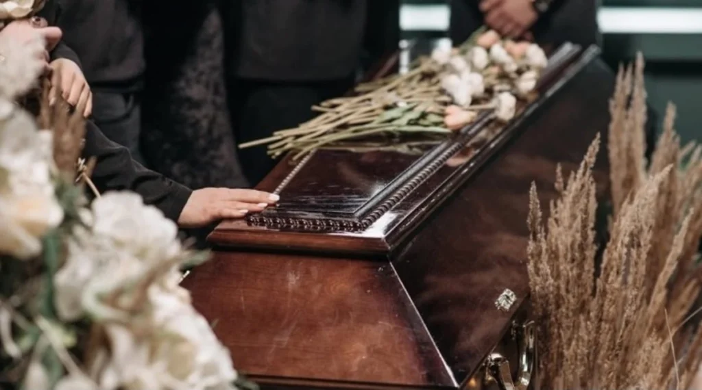 Persone riunite durante una cerimonia funebre all'aperto per l'ultimo saluto a un caro