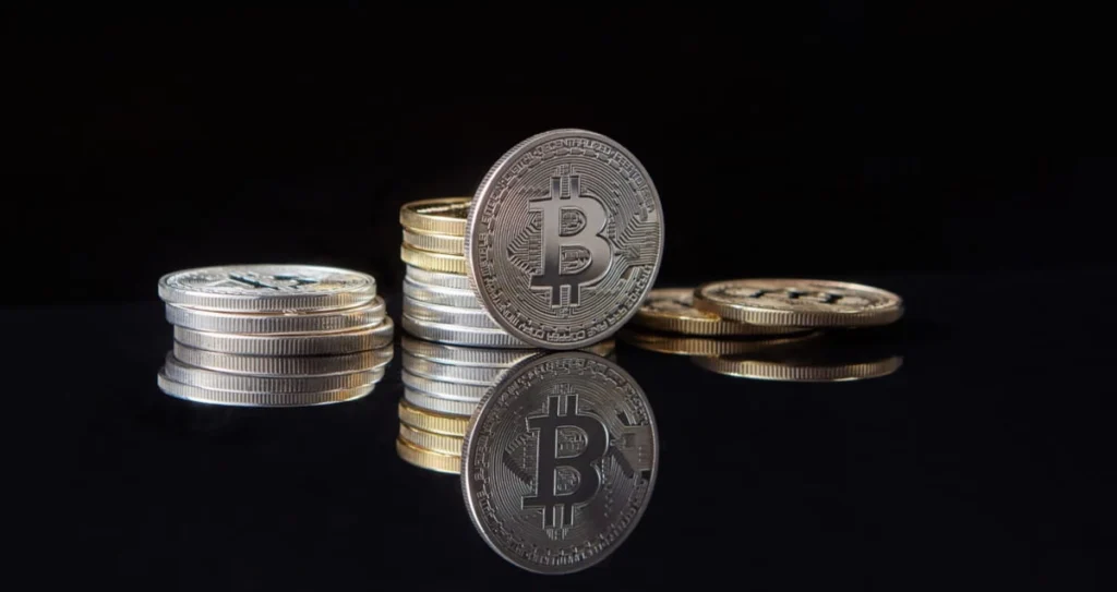 Moneta fisica di Bitcoin in argento posizionata verticalmente su sfondo bianco neutrale
